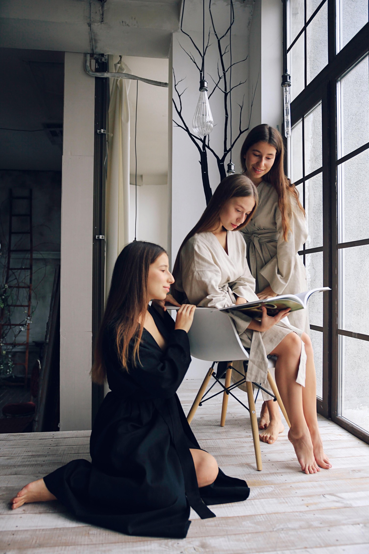 Three models reading by tall windows in Veresk Clothes robes